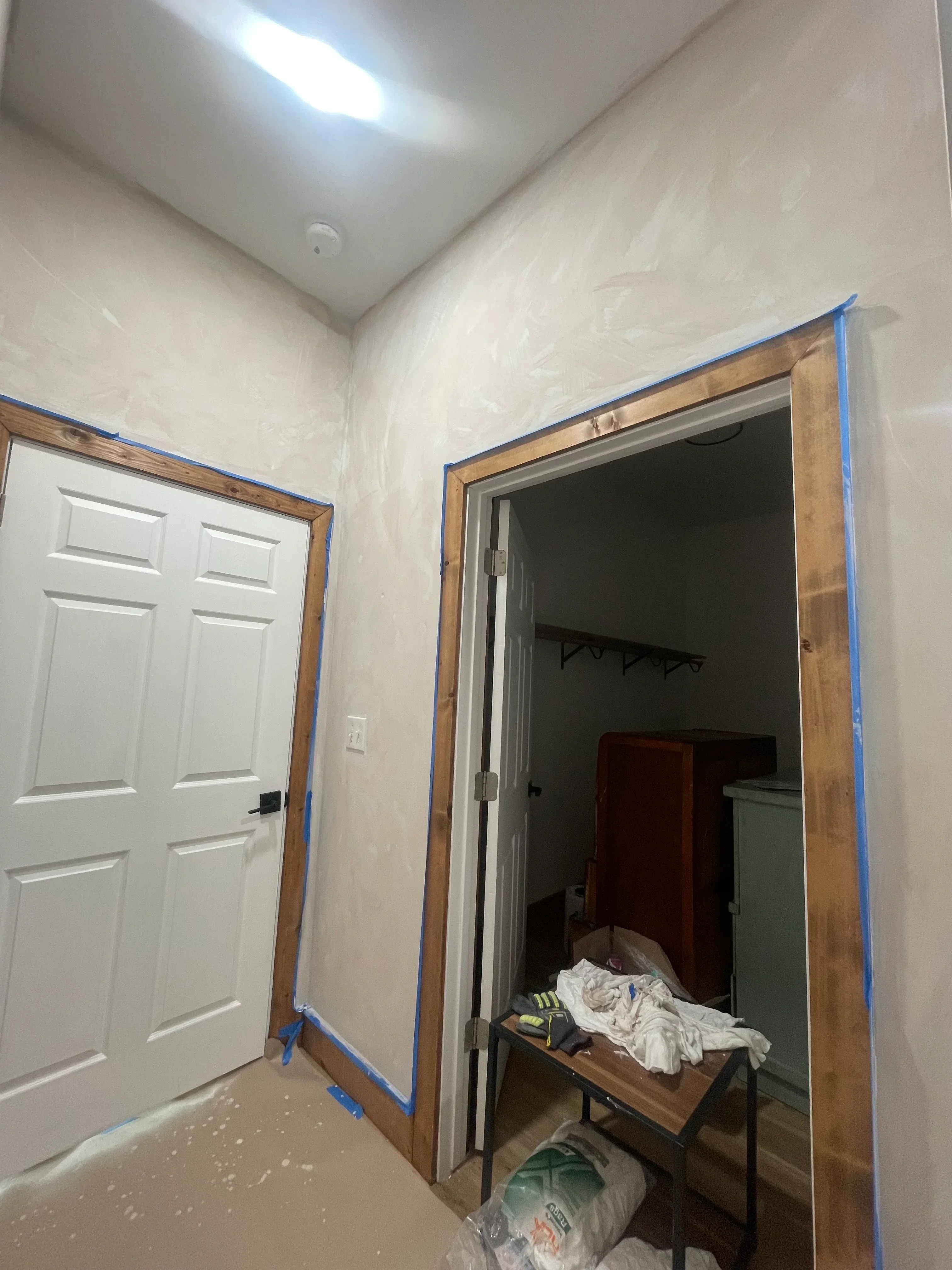 Garage epoxy flooring installation with blue masking tape and protective coverings on walls and door frame