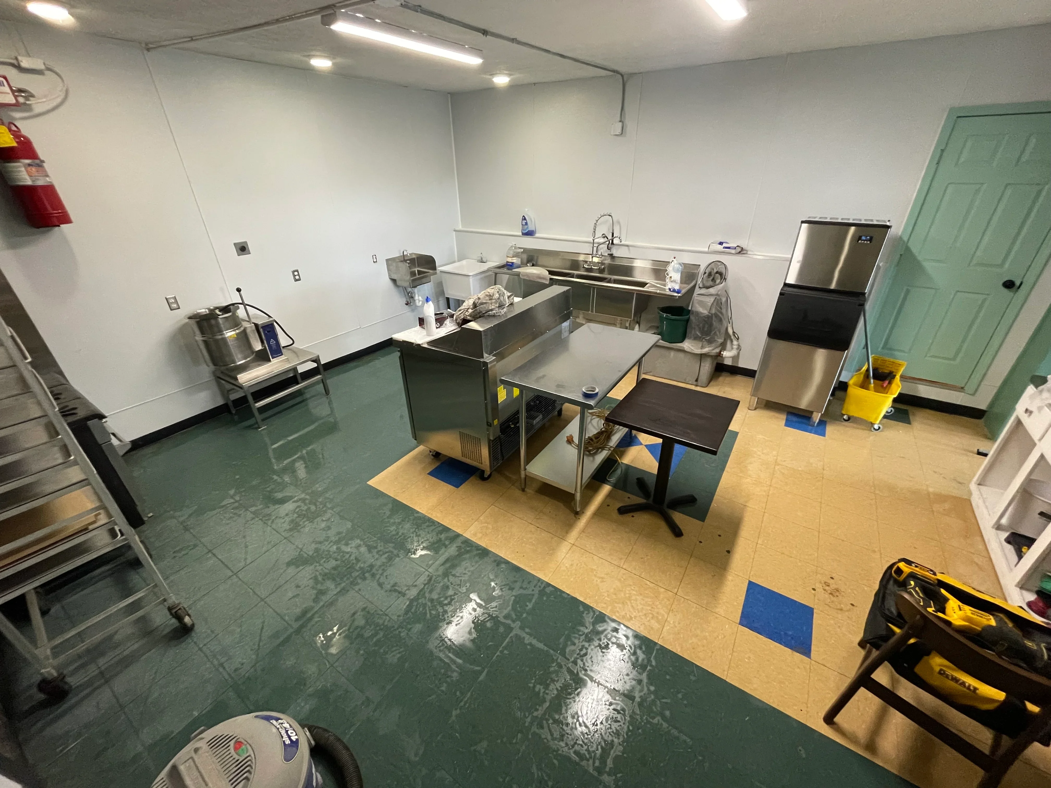Commercial kitchen with two-tone green and tan epoxy flooring, stainless steel sinks and equipment