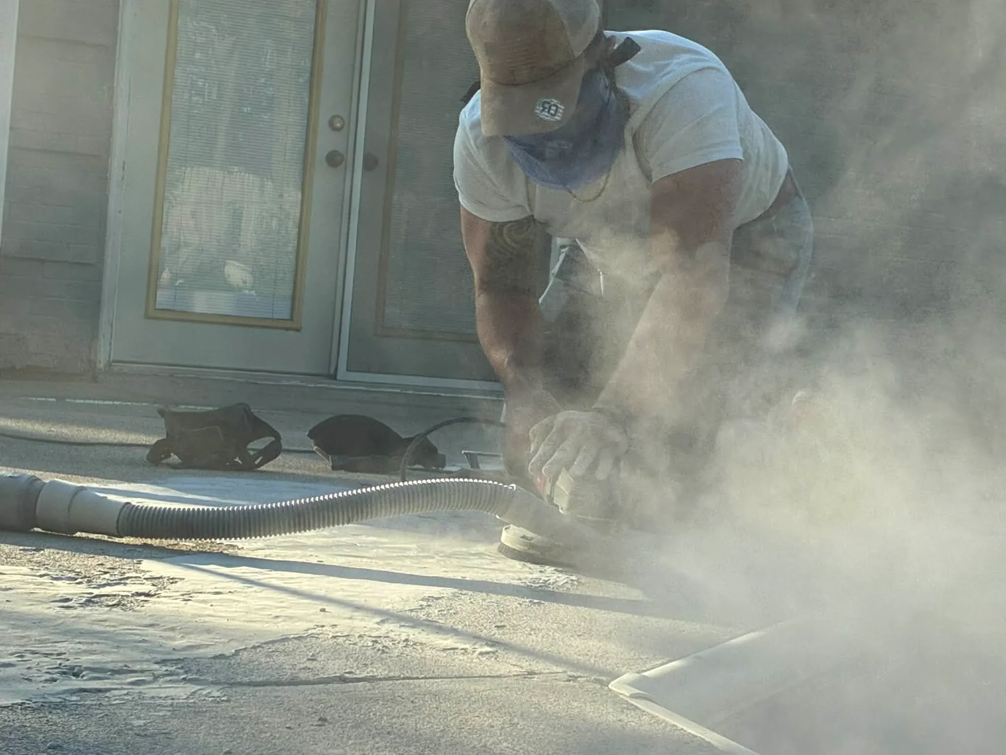 Worker grinding concrete floor with dust collection for epoxy flooring preparation
