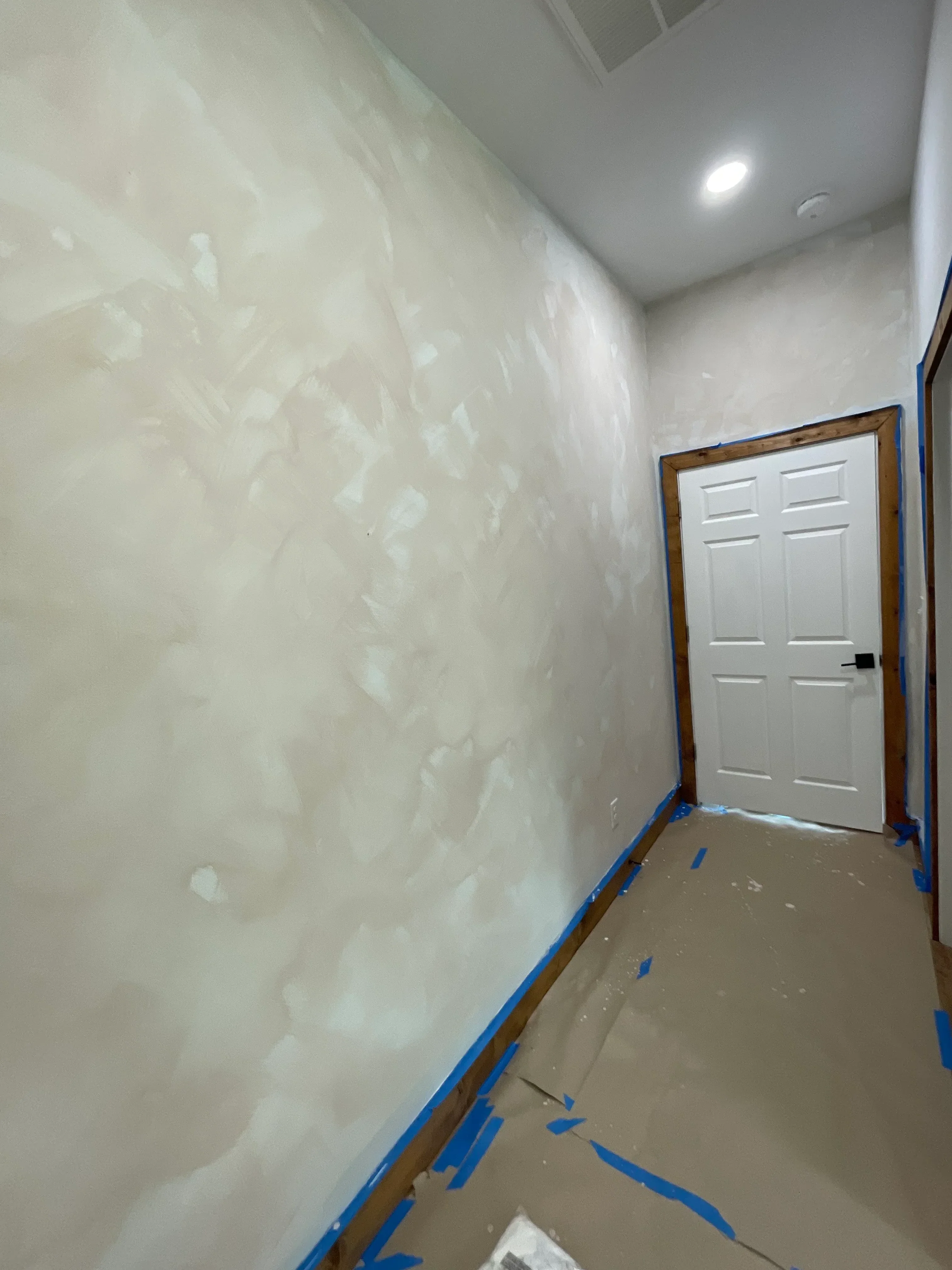 Garage interior with newly applied epoxy floor coating, blue masking tape, white garage door
