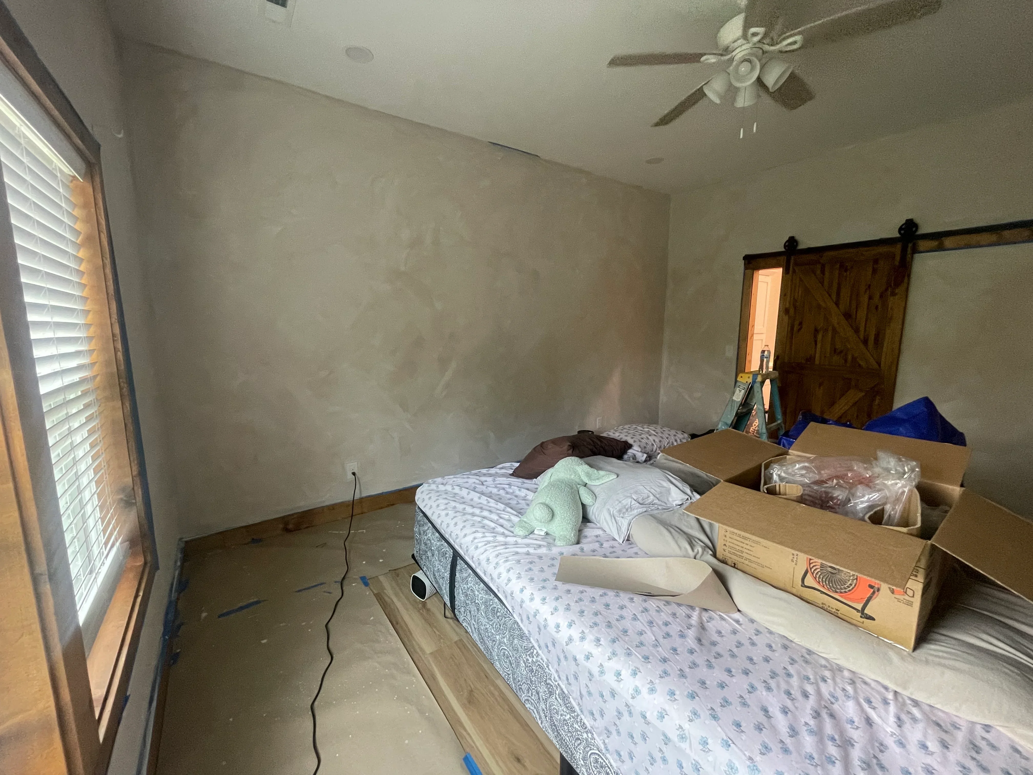 Bedroom with epoxy flooring installation, concrete base coat, protective coverings on furniture