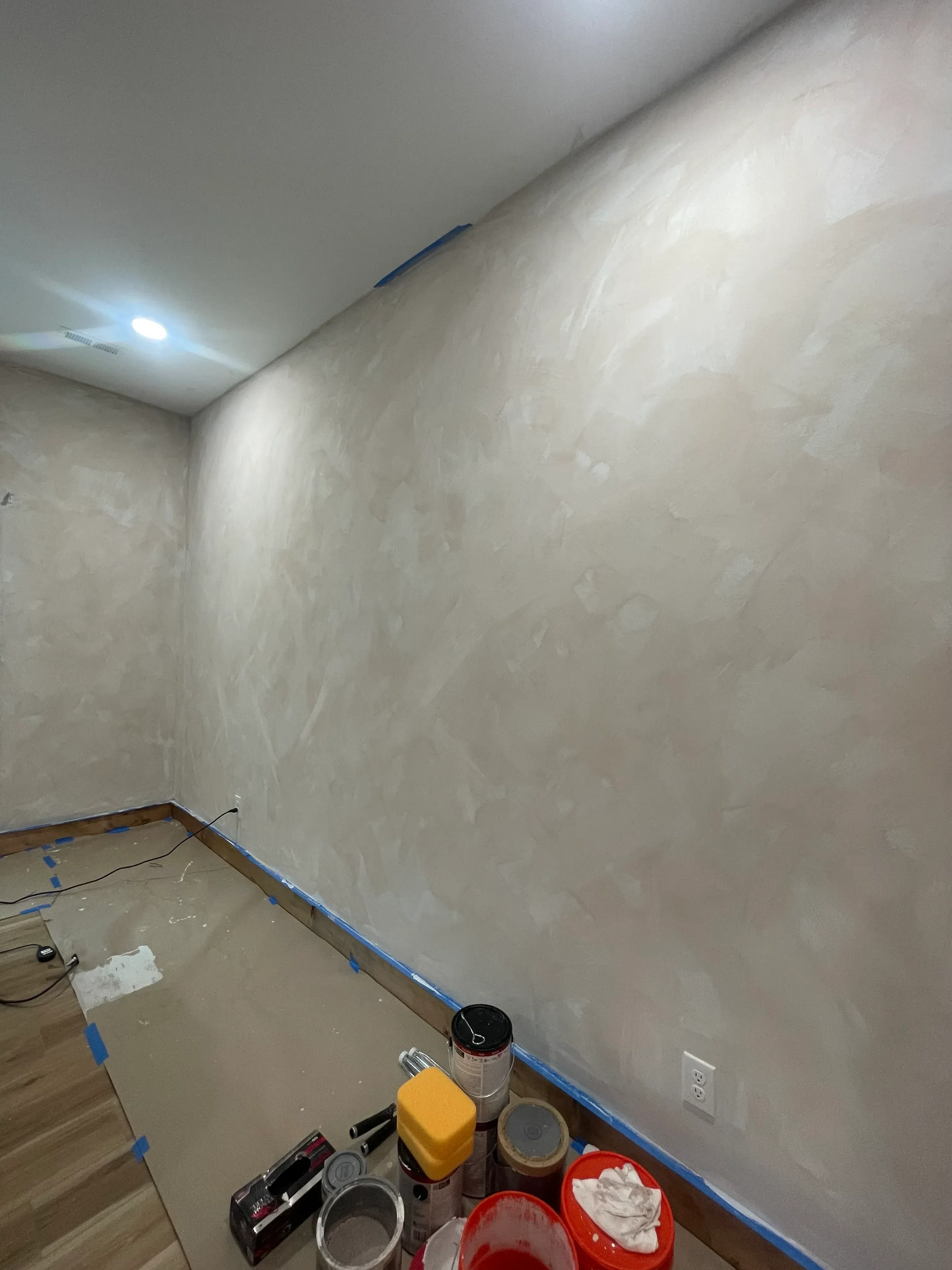 Drywall ceiling and walls with joint compound taping and mudding in progress, blue painter's tape along edges