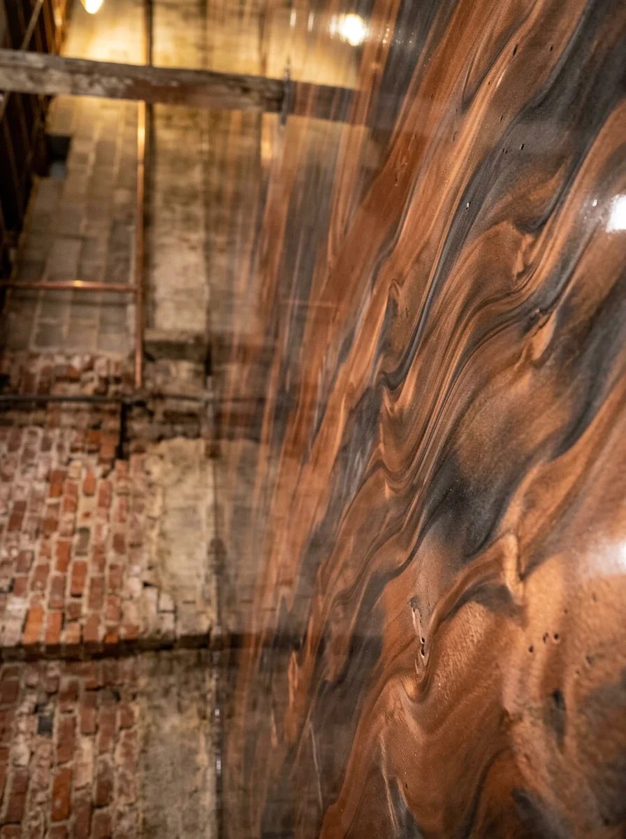 Close-up portrait view of a metallic epoxy floor in a Louisville basement, showing swirling copper and charcoal tones on a smooth, sealed concrete surface.